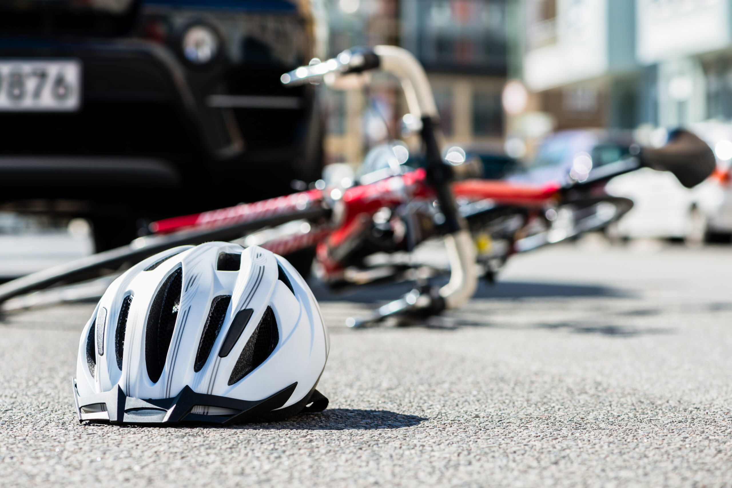 Close-up of a bicycling helmet on the asphalt  next to a bicycle